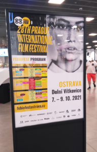 Plakát se zakomponovaným programem festivalu umístený v obchodním centru.